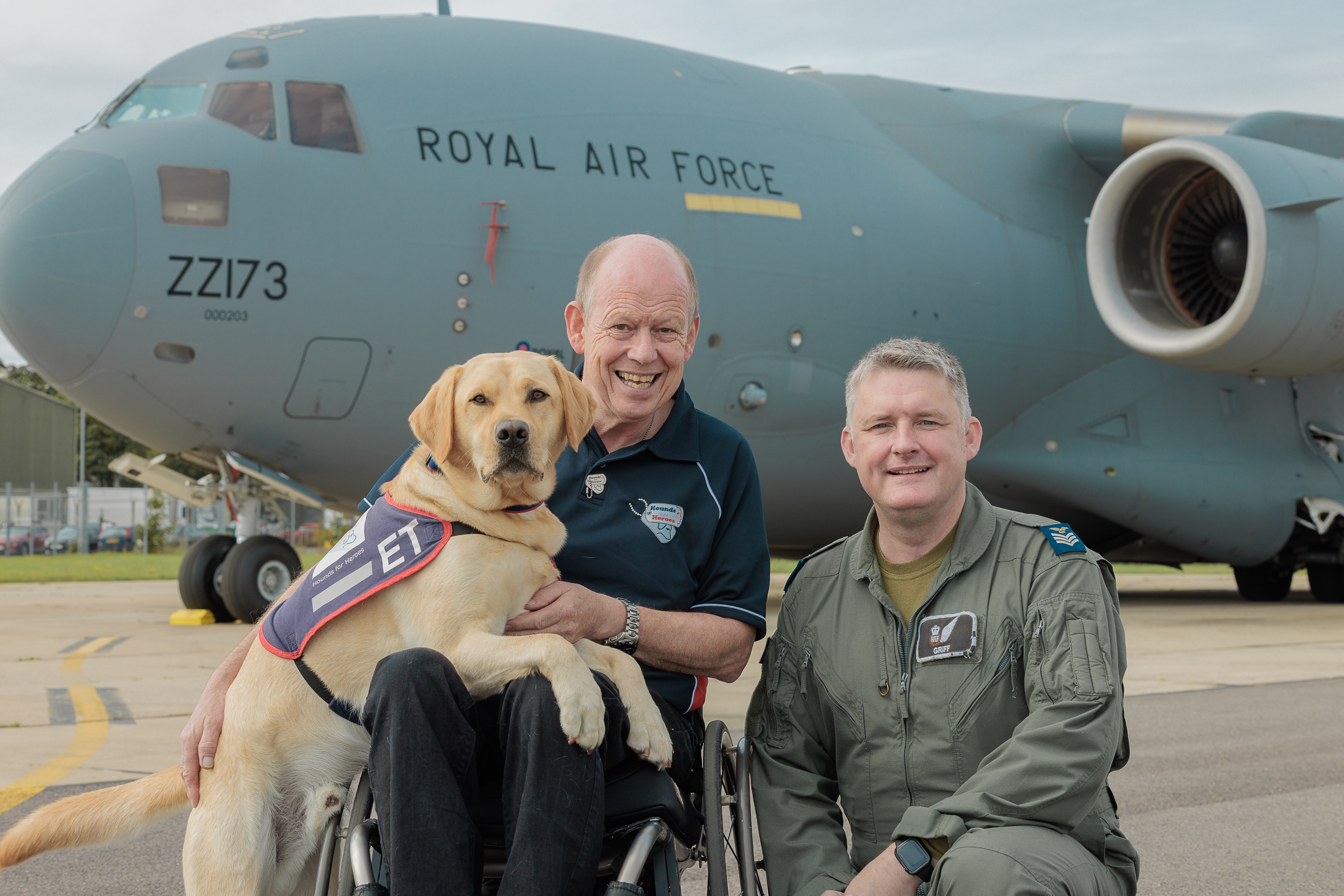 Photo - Hounds for Heroes founder Allen Parton and assistance dog ET posed with 99 Squadron aircrew in front of a Globemaster (C-17) aircraft